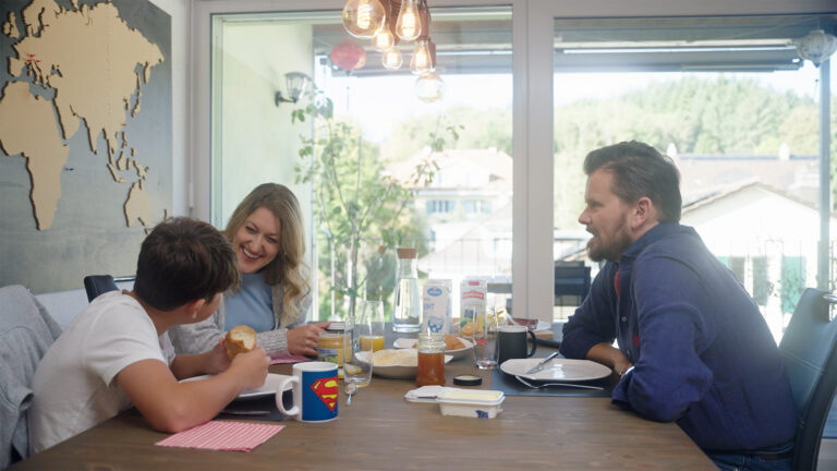 Commercial: a happy family sitting at the table eating breakfast